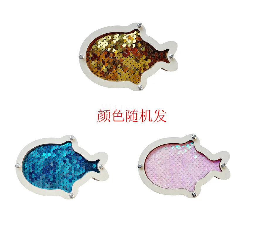 A silver-colored fish-shaped charm covered in gold glitter and a pink fish-shaped charm covered in pink glitter.