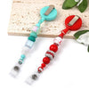 A set of beadable badge reels with retractable clips in teal and red colors displayed on a light wooden surface.