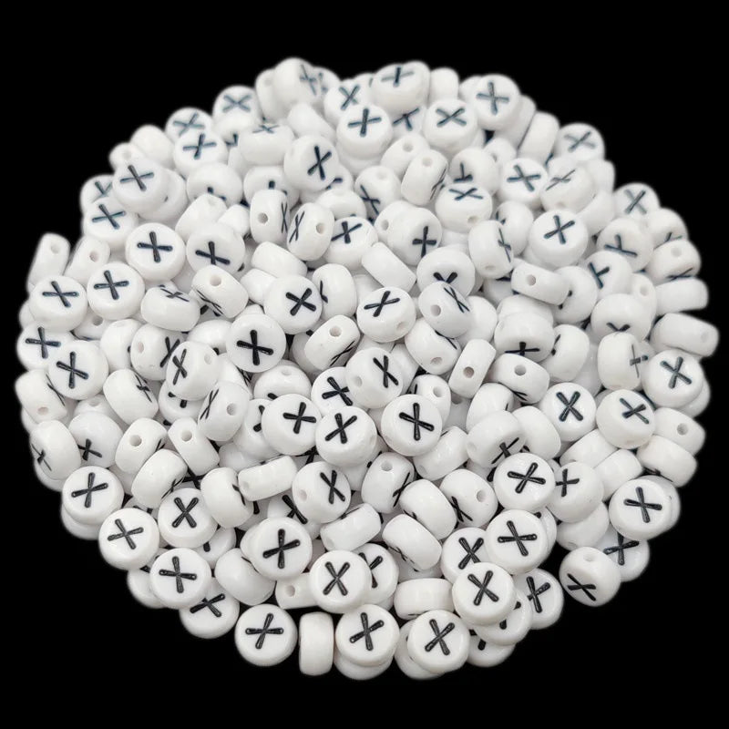 A pile of small white acrylic alphabet letter beads with black markings for jewelry making