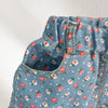 A close-up of a girl's blue floral print sleeveless shirt and shorts set with gathered fabric details.