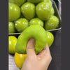 A hand holds a bright green, oval stress ball next to a tray of similar green balls.