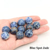 A hand holds several blue spot jade crystal spheres.
