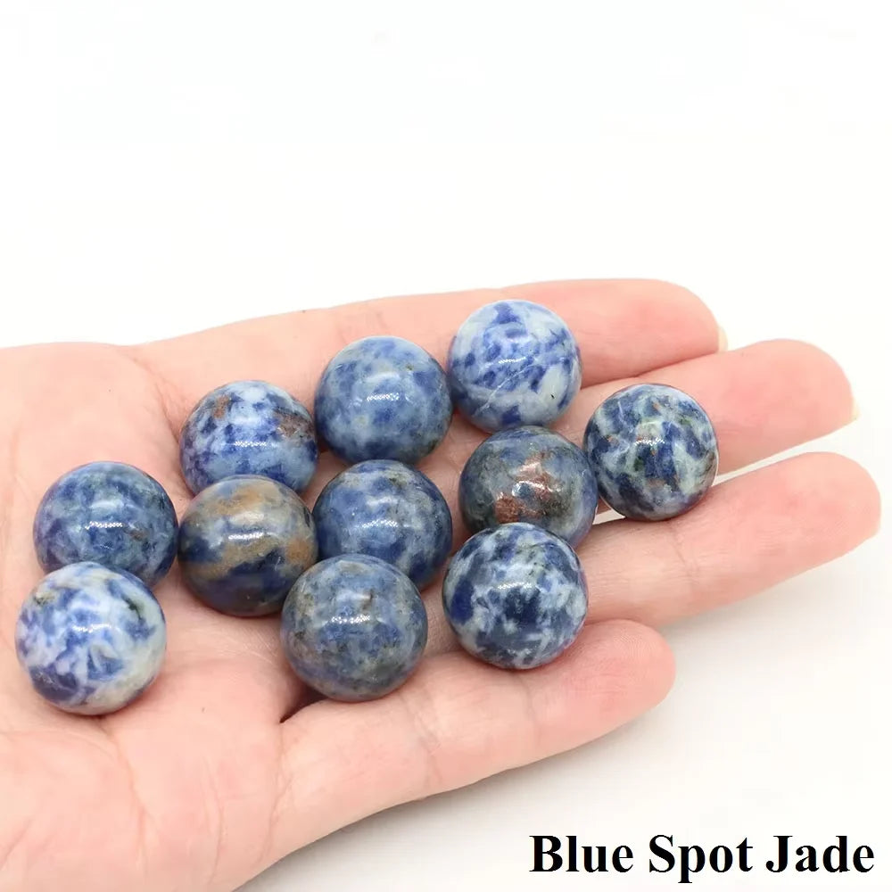A hand holds several blue spot jade crystal spheres.