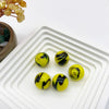Perles de verre marbrées jaune et noir arrangées dans un plateau blanc.
