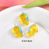 Two yellow and blue resin charms shaped like sea creatures are displayed on a white plate.