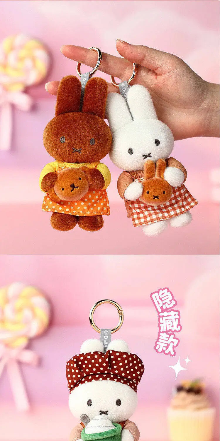 A white Miffy plush keychain charm with brown ears and a yellow outfit is being held by a hand.