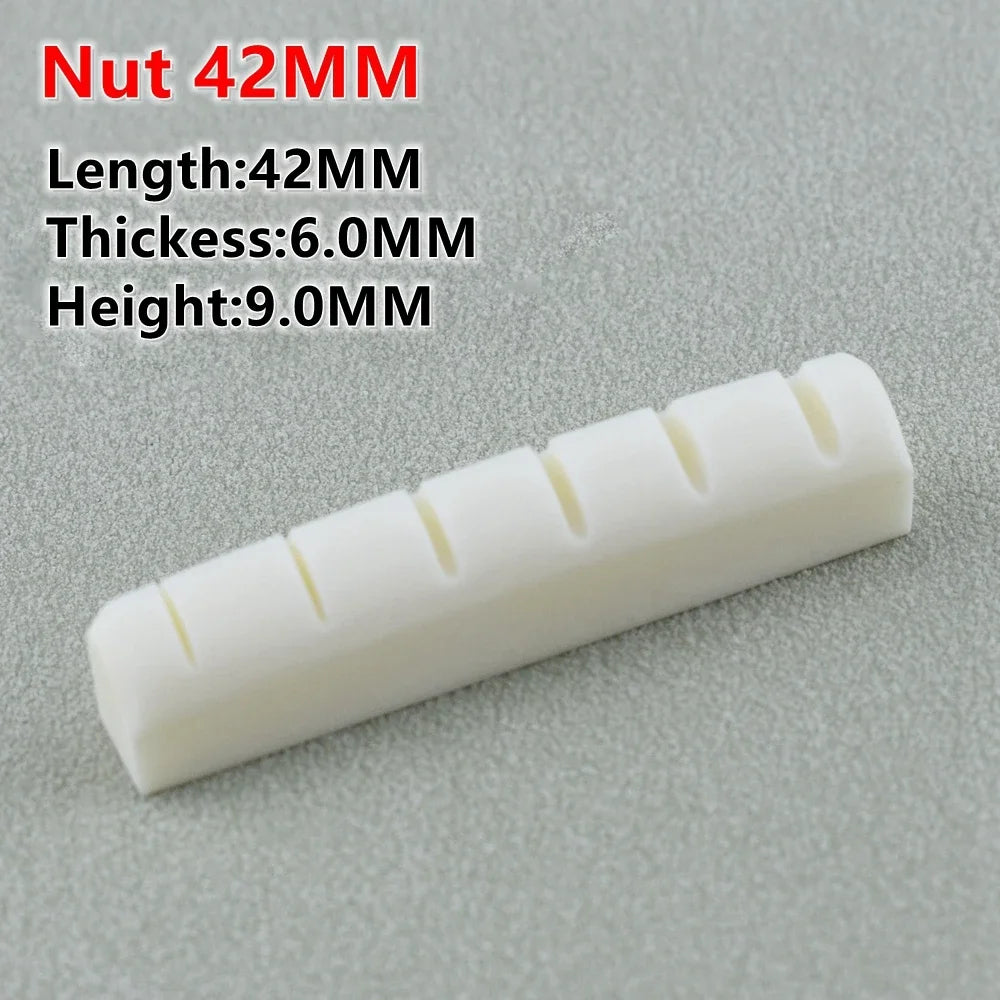 White guitar nut with four grooves shown against a gray background