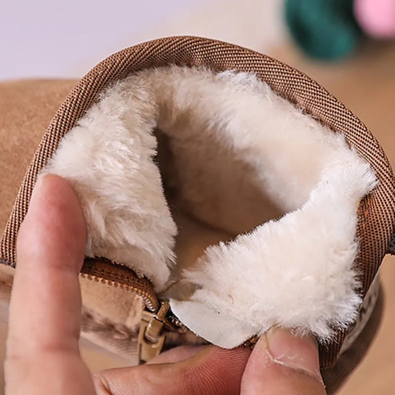 A hand is opening a tan faux fur lined winter snow boot to show the soft white sherpa lining.