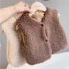 A brown plush fleece vest hanging on a wooden hanger next to a cream-colored one.