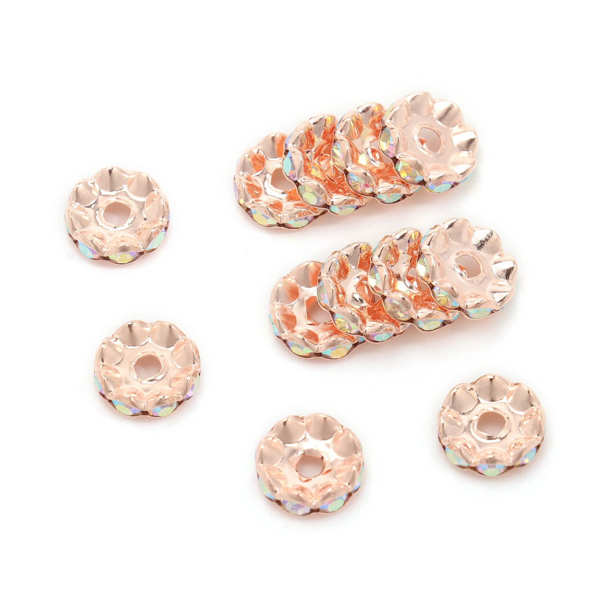 A collection of 12mm crystal rhinestone spacer beads in a rose gold tone, arranged in rows and individual pieces.