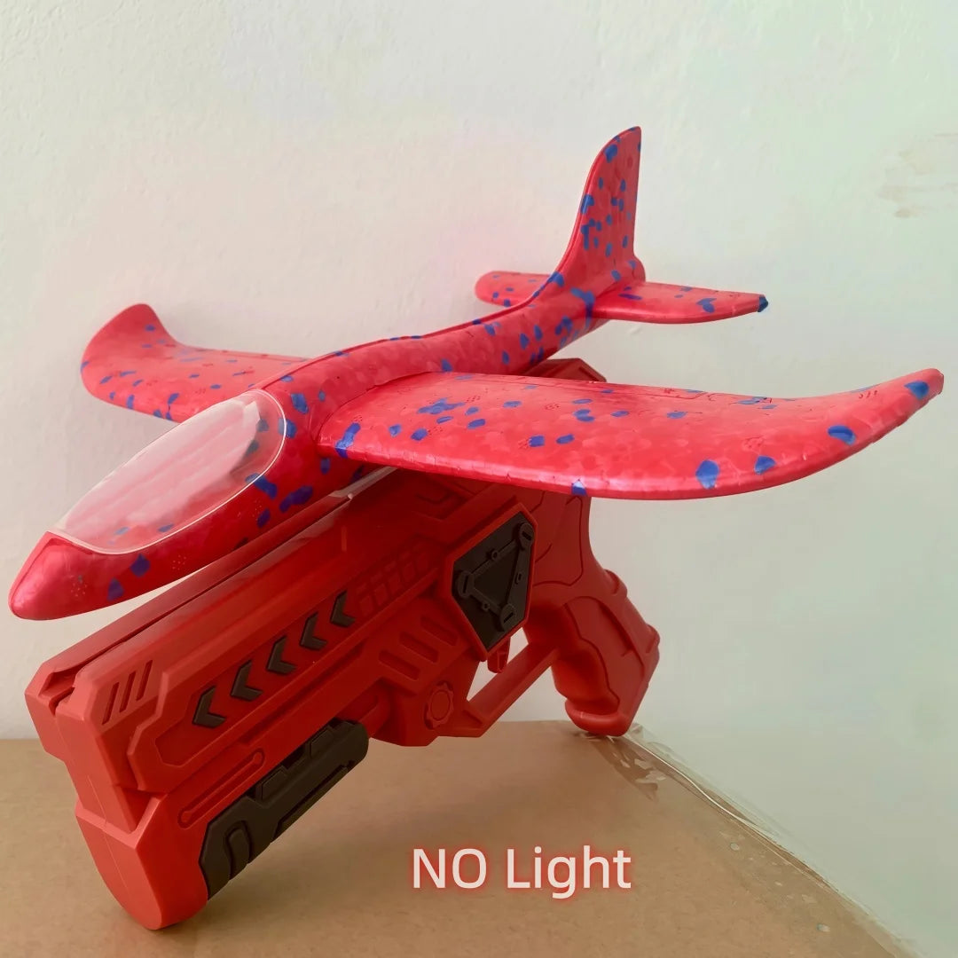 A red foam glider catapult toy gun with a wing and firing mechanism, shown against a light background.