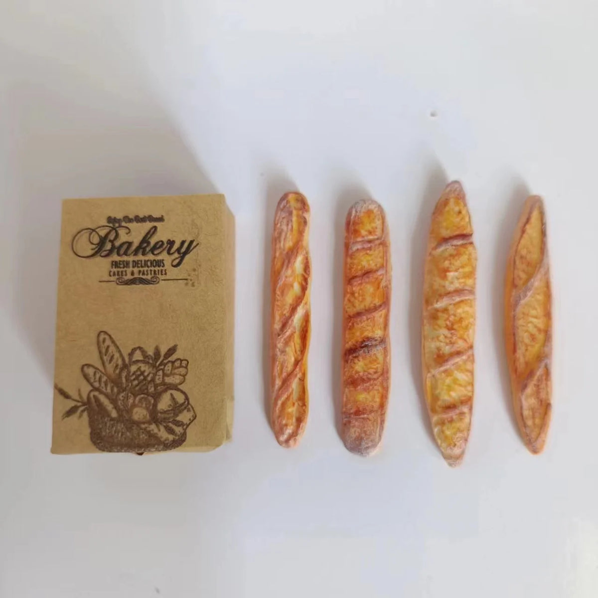 Three miniature baguette loaves are displayed next to a brown bakery tag.