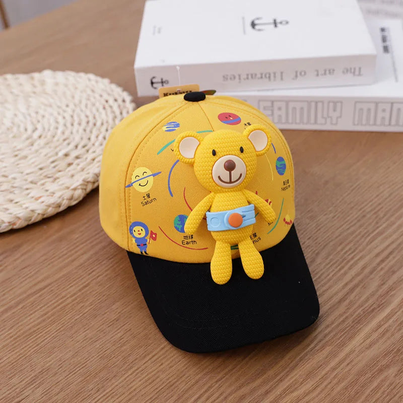 A yellow toddler bear baseball cap with an adjustable strap resting on a wooden surface.