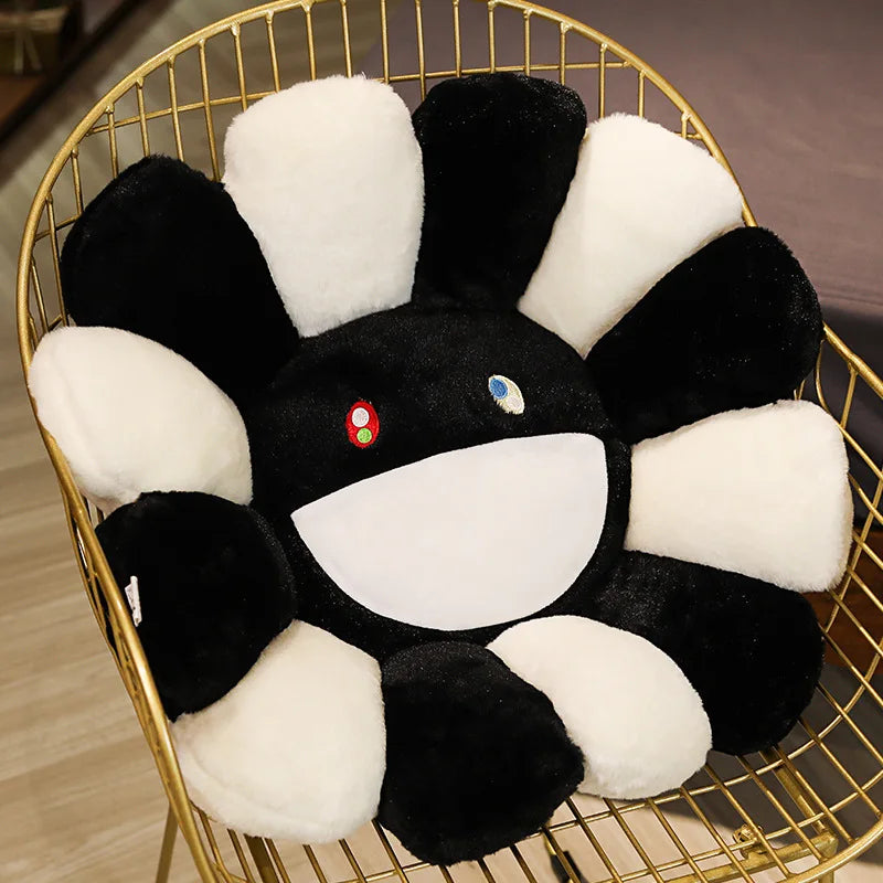 A large sunflower plush cushion with black and white petals is displayed in a gold wire basket.