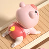 A pink piggy-shaped baby crawling toy is shown simulating crawling action on a wooden surface.