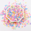 A pile of colorful polymer clay sprinkles in various shades of pink, blue, yellow, and purple.