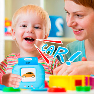 A smiling toddler is interacting with a woman while playing with a blue talking flash card car toy.