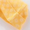 A close-up of yellow knitted baby hats featuring a repeating white sun pattern.