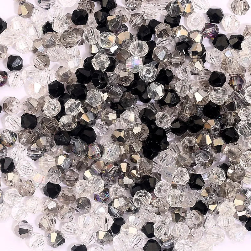A pile of clear and black faceted crystal bicone glass beads for jewelry making.