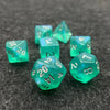 A set of seven iridescent green acrylic polyhedral dice resting on a dark surface.