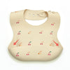 A beige soft silicone waterproof baby bib with an adjustable neck and small fruit graphics.