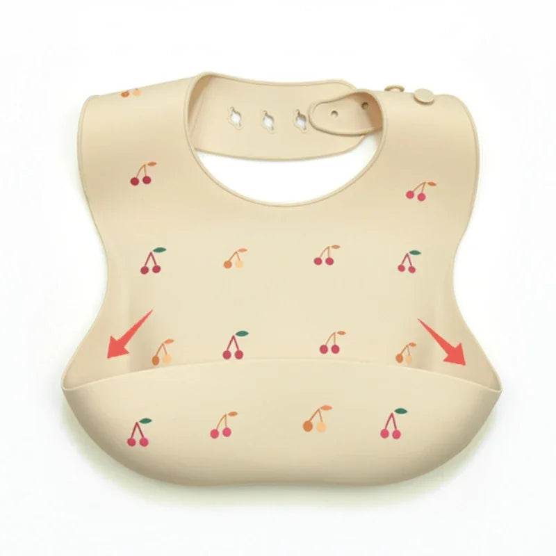 A beige soft silicone waterproof baby bib with an adjustable neck and small fruit graphics.