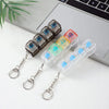 A set of four colorful LED keyboard fidget toys with metal chains displayed on a white surface next to a laptop.