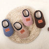 Three pairs of cozy plush baby slippers in pink, beige, and brown resting on a woven mat.