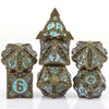 A set of seven metal dice featuring a skull and dragon design in bronze and teal colors.