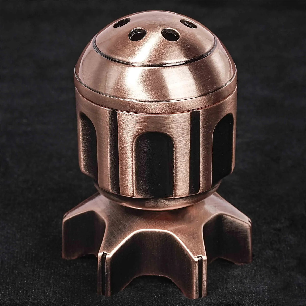 Juego de dados poliedrales de metal bronce con tapa de cúpula y base, mostrado contra fondo oscuro.