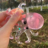 A hand holds a clear, pink stretchable octopus stress ball with star confetti details outdoors.