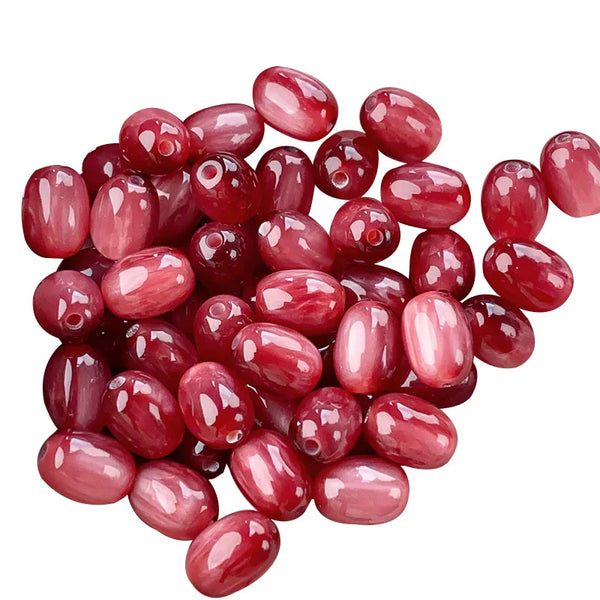 Un tas de perles résine œil-de-chat rose-rouge brillantes, motif ciel étoilé, pour création de bijoux.