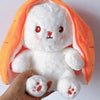 A white plush bunny toy with bright orange ears and face being held by a hand.