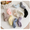 Three pairs of soft fleece socks in various pastel and neutral colors laid out on a white surface.