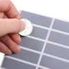 A hand places a coin onto a sheet of scratch-off sticker paper for DIY cards or games.