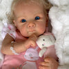 A close-up of an 18-inch lifelike reborn baby doll with hand-rooted hair wearing a pink outfit.