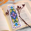 A colorful cross-stitch bookmark craft kit featuring floral designs on a page of a book.