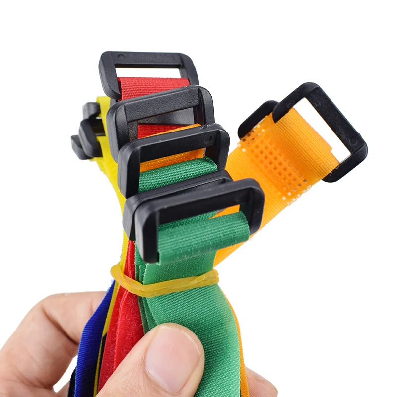 A hand holds a set of five nylon bike handlebar straps in various colors including black, red, yellow, and green.