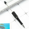 A black beaded ballpoint pen is shown resting on a white surface next to a notebook.