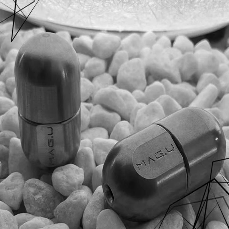 A close-up shot of a metallic magnetic levitating fidget slider resting among small, light-colored pebbles.