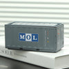 A gray industrial storage box labeled MOL resting on a white surface.