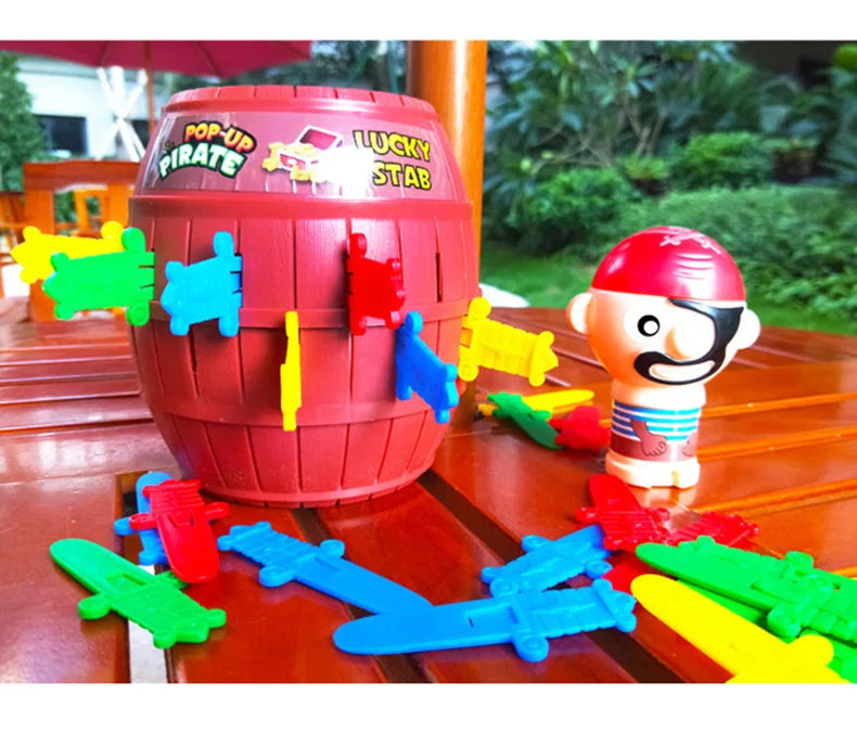 A red barrel decorated with pirate themes and various plastic sword and stab accessories for a party game.