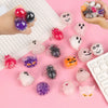A collection of five Halloween squeeze stress balls in various colors and textures are displayed on a pink background.
