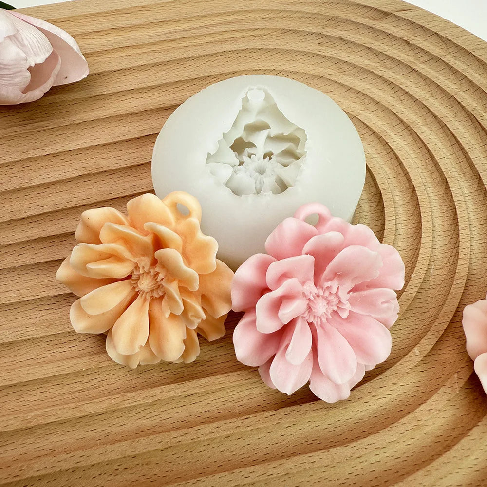 A silicone mold shaped like a carnation flower in peach and pink colors rests on a wooden surface.