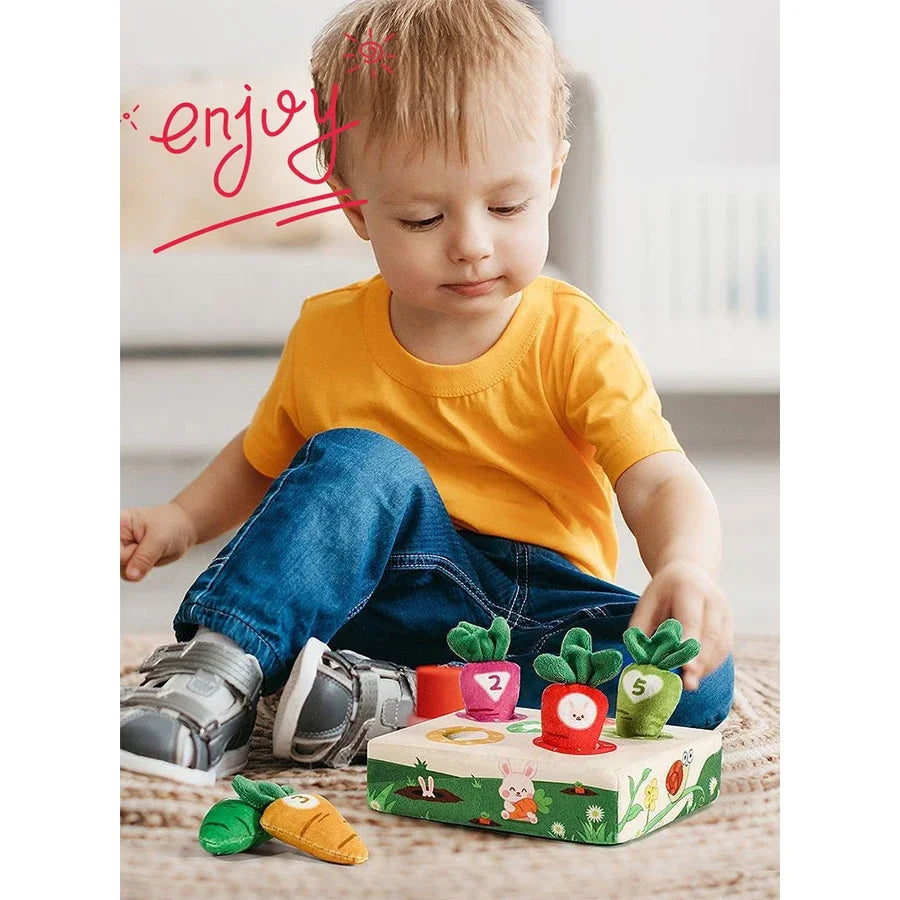 A toddler is playing with a Montessori carrot pull toy, which is soft and washable for sensory learning.