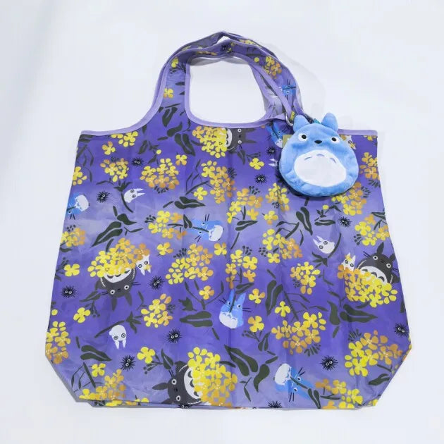 A purple fabric tote bag featuring a yellow floral pattern and a blue cartoon hippo plush toy.
