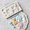 A set of white silicone baby-themed cake molds including a stroller, bottle, pacifier, and teddy bear shapes.