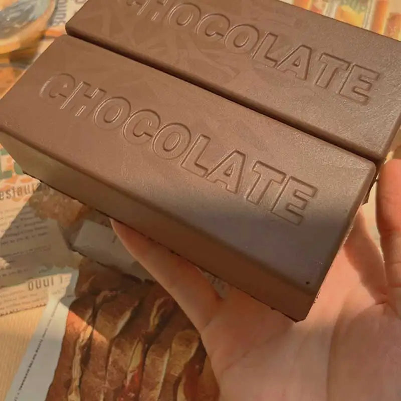 A hand holds a brown chocolate sensory squishy fidget toy box with the word CHOCOLATE embossed on it.