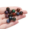 A hand holds several round, polished resin beads in various colors including purple, green, brown, and blue.