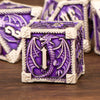 A purple metal die with a dragon design and silver trim, part of a premium dice set.